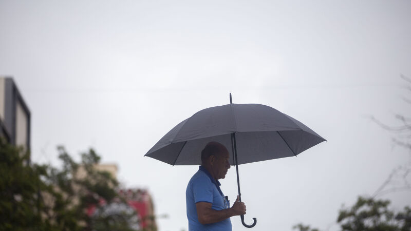 Homem com guarda-chuva se protegendo da chuva