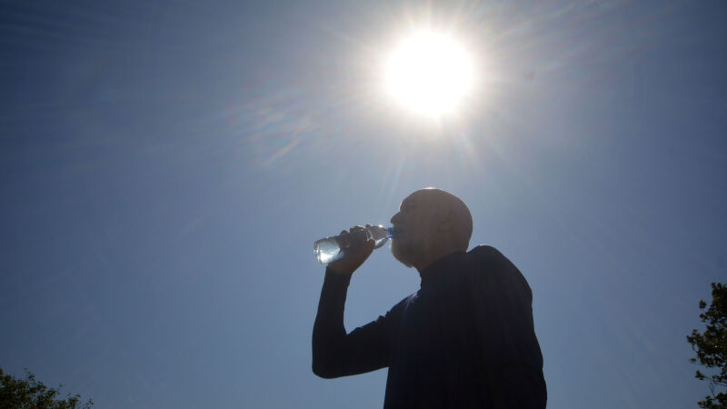 Homem bebendo água para se hidratar no calor