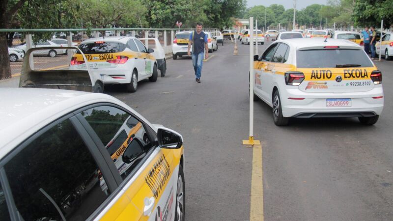 Veículos de autoescola aguardam a realização de exames práticos no Detran-MS; nova regra permite aprovação com até dez pontos.