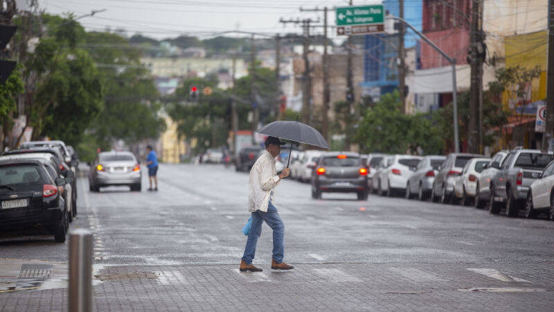 Campo-grandense se protegendo da chuva com uma sombrinha