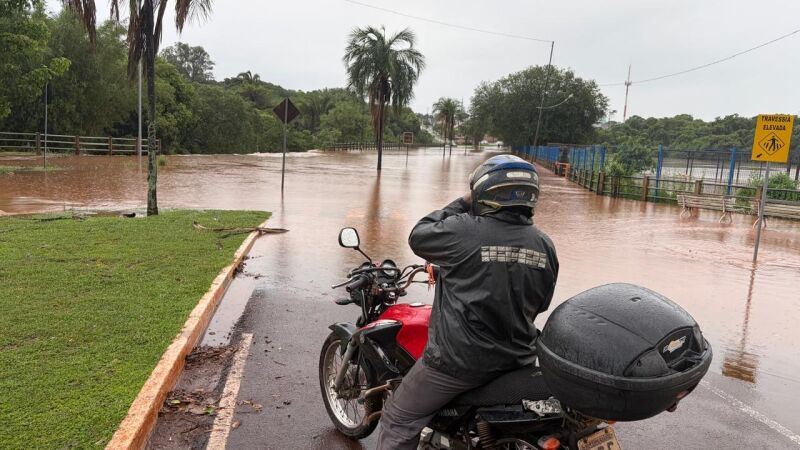 Motociclista observa via tomada pela água após as fortes chuvas que atingiram Campo Grande nesta quinta-feira (15).